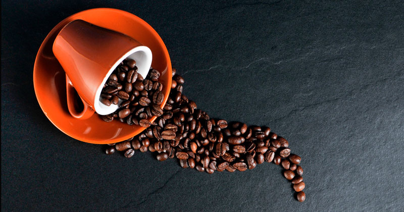 Cuánta cafeína tiene el café. Blog La Boutique del café. Taza volcada con granos de café esparcidos.